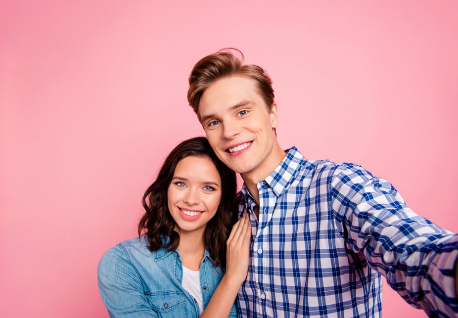 A young couple posing for an Instagram photo.