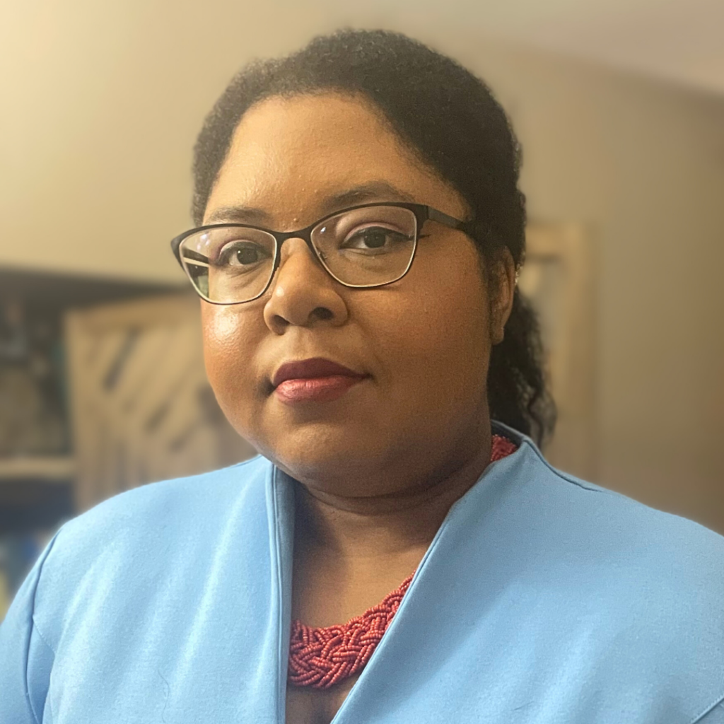 Picture of Monique wearing a blue dress and orange necklace