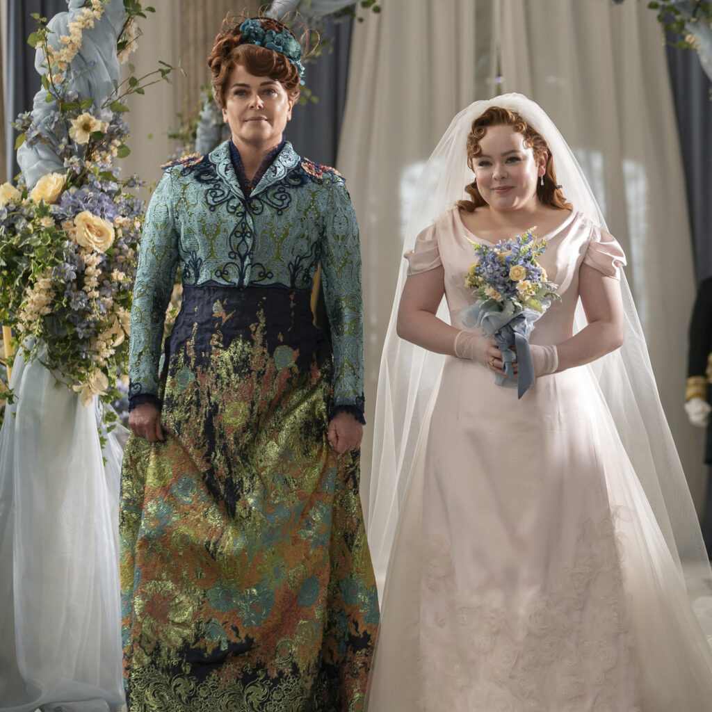 Polly Walker as Lady Portia Featherington, Nicola Coughlan as Penelope Featherington. Portia is walking Penelope down the aisle. 