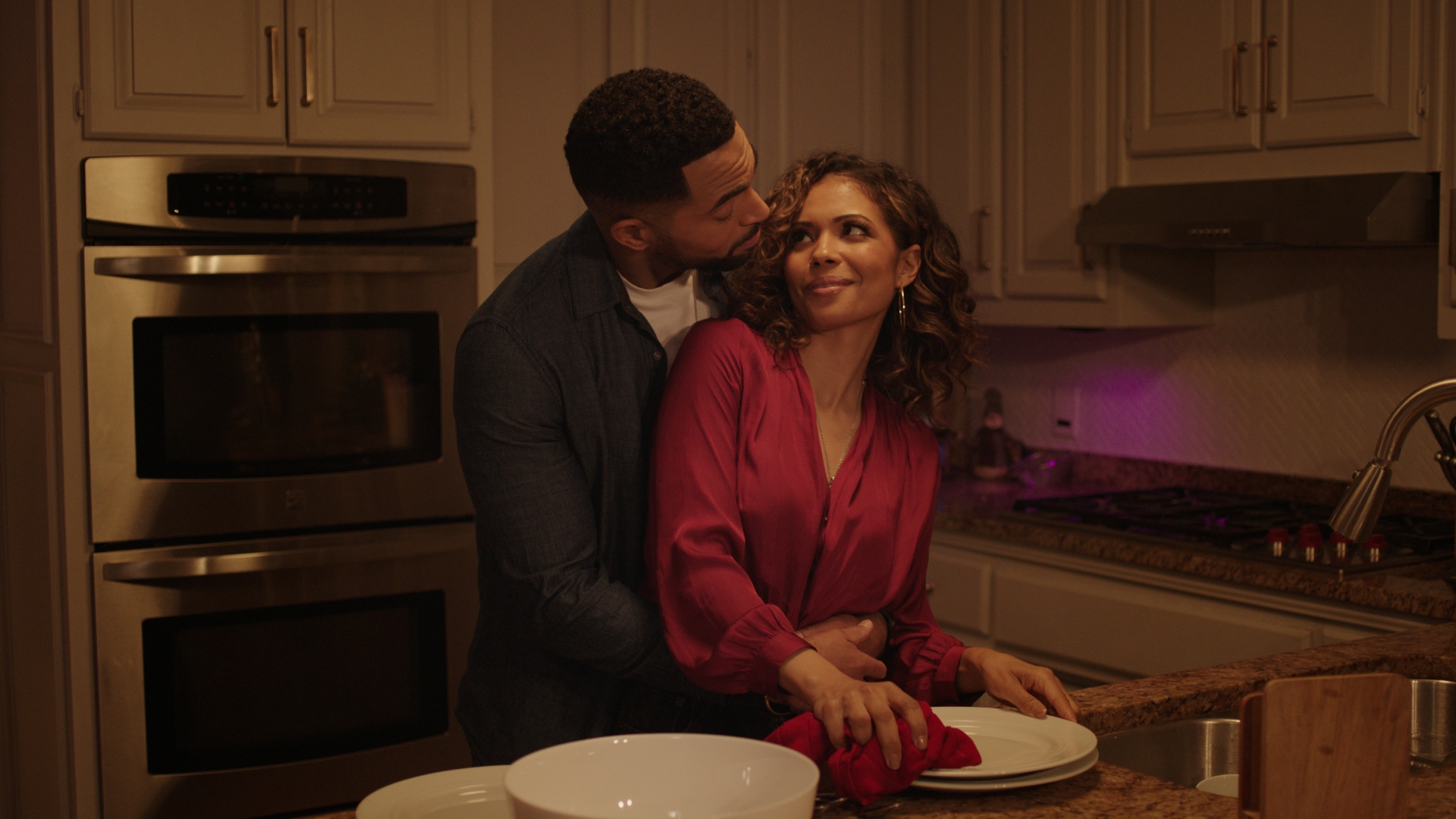 Jennifer Freeman and Anthony Dalton hug together in the kitchen.