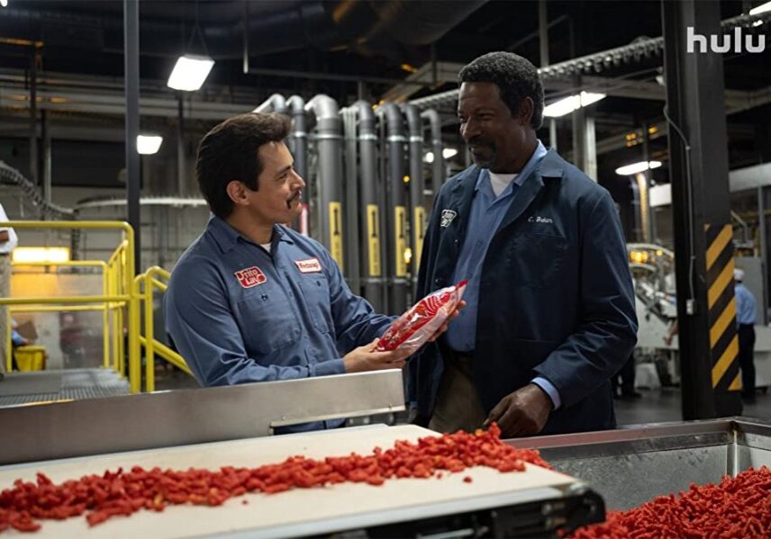 Jesse Garcia and Dennis Haysbert stand next to a line of Flamin' Hot Cheetos